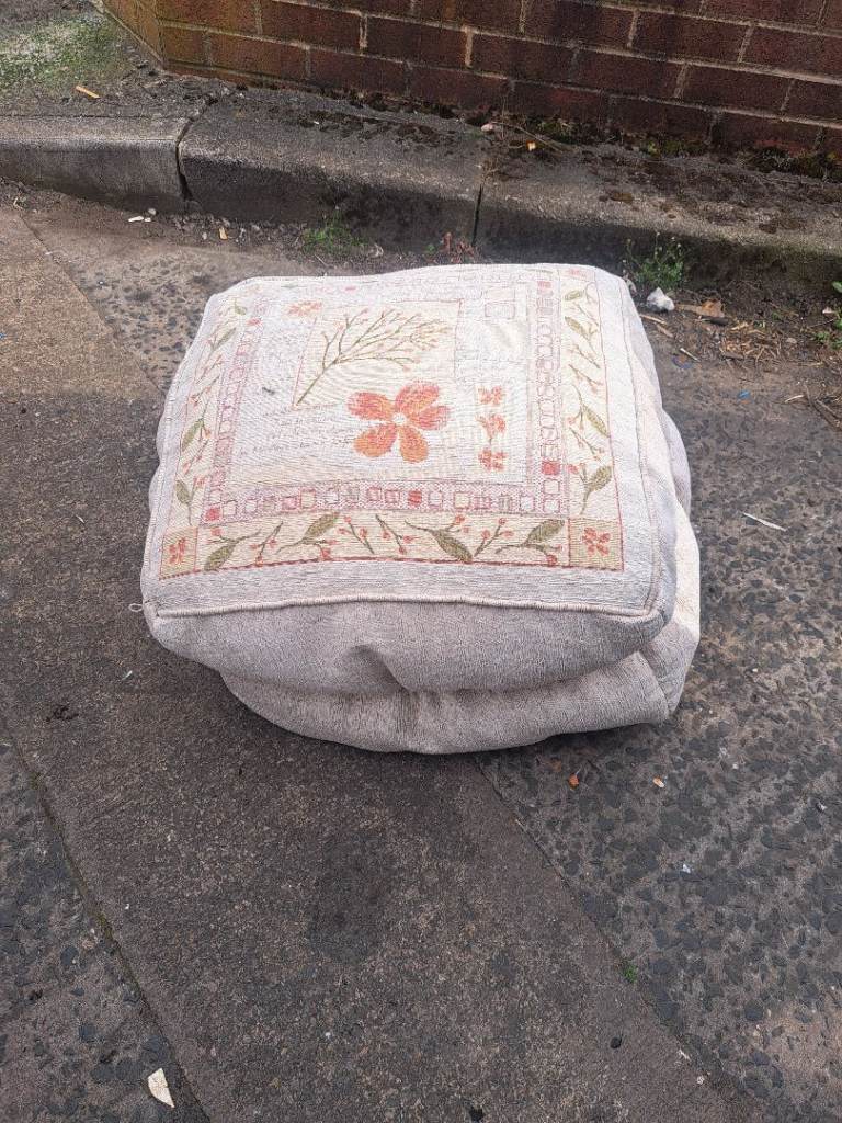 beige fabric either bean bag or foot rest with picture on the top