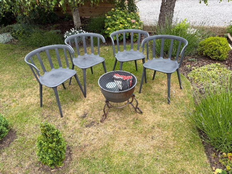 Cast iron fire pit and 4 black garden chairs.