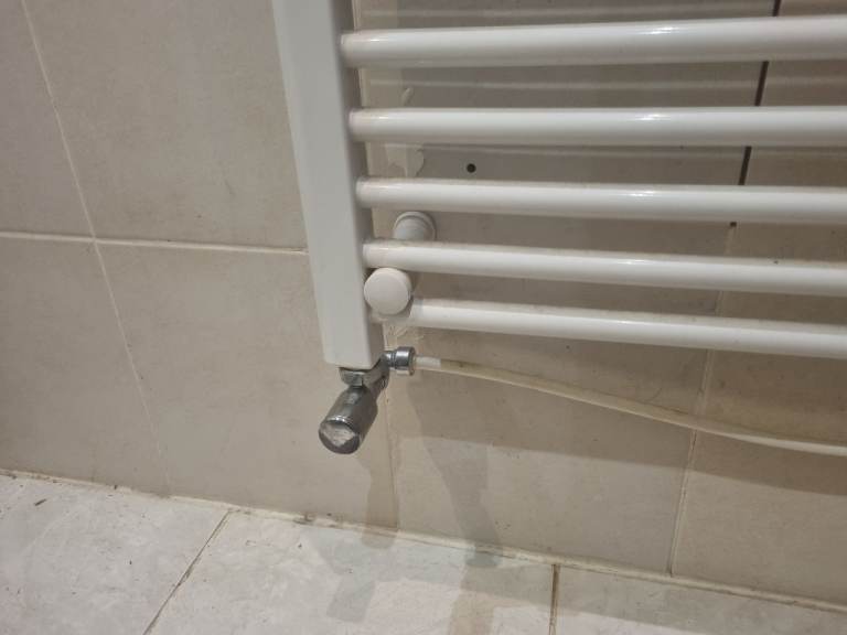 White straight towel radiator with chrome valves.