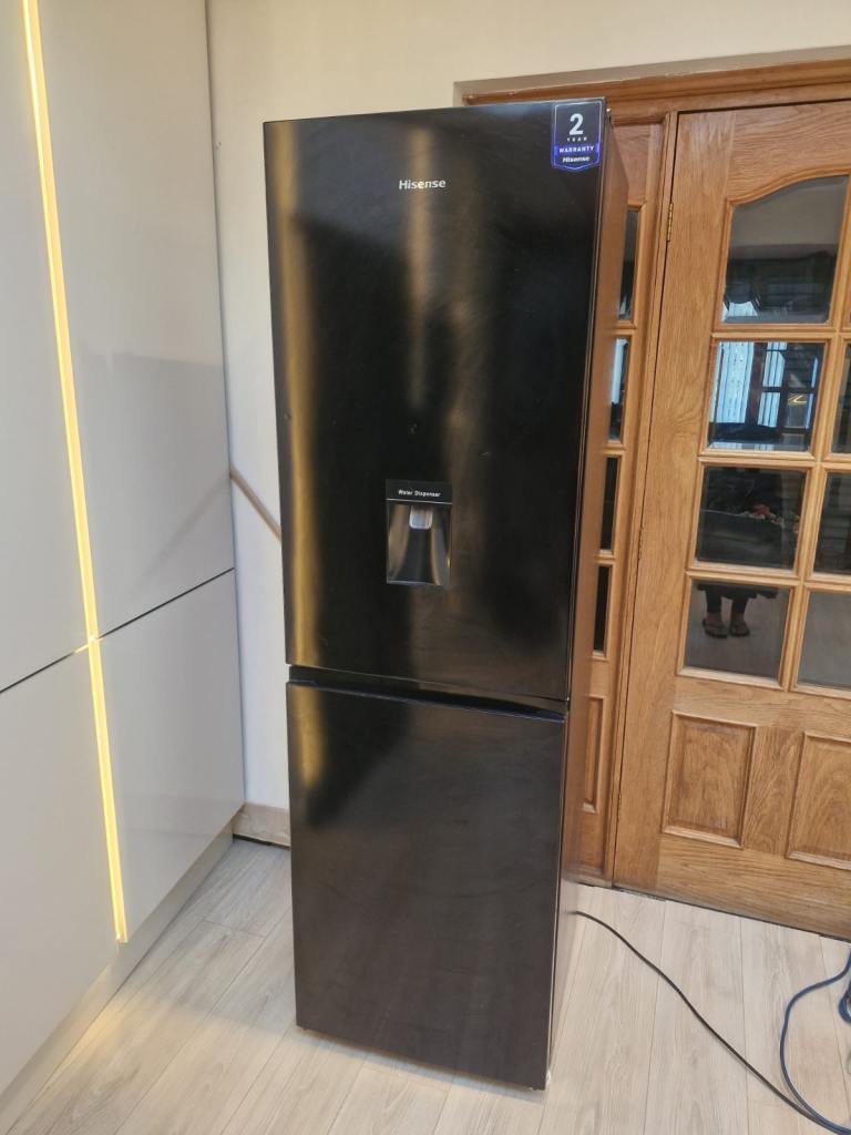 Black Hisense fridge freezer with built-in water dispenser.
