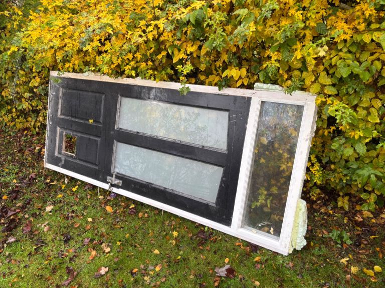 Front door black panelled wooden, with cutout for cat flap and frame