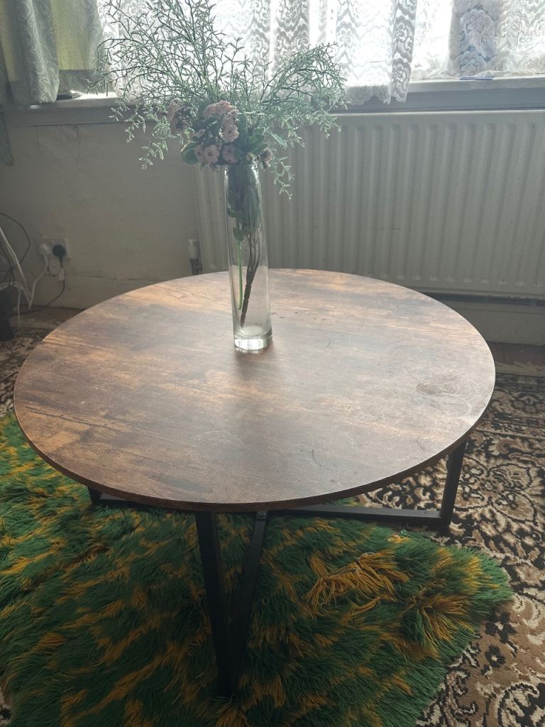 A round coffee table with a wooden top and black metal legs