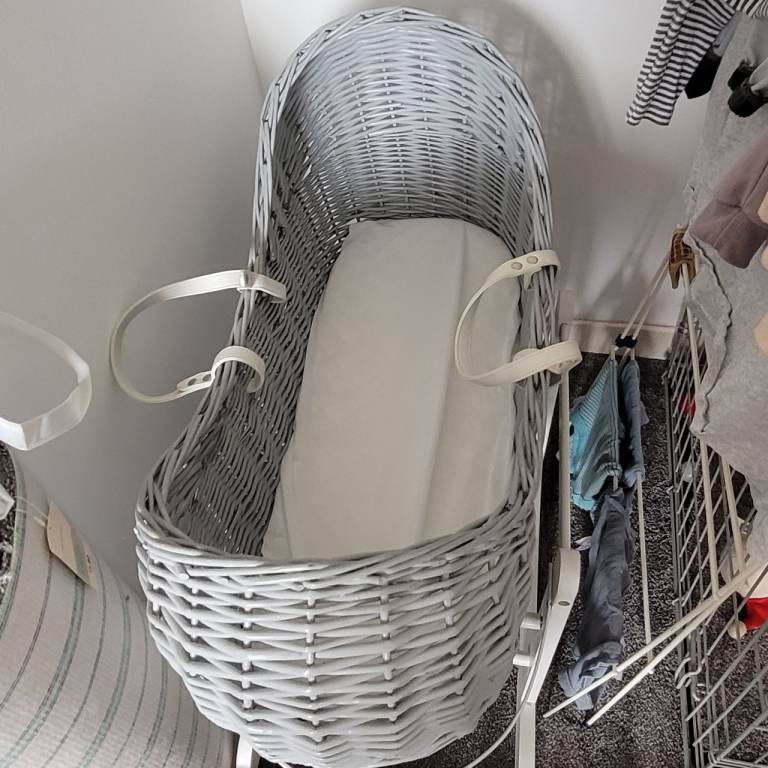 grey moses basket with white rocking stand 