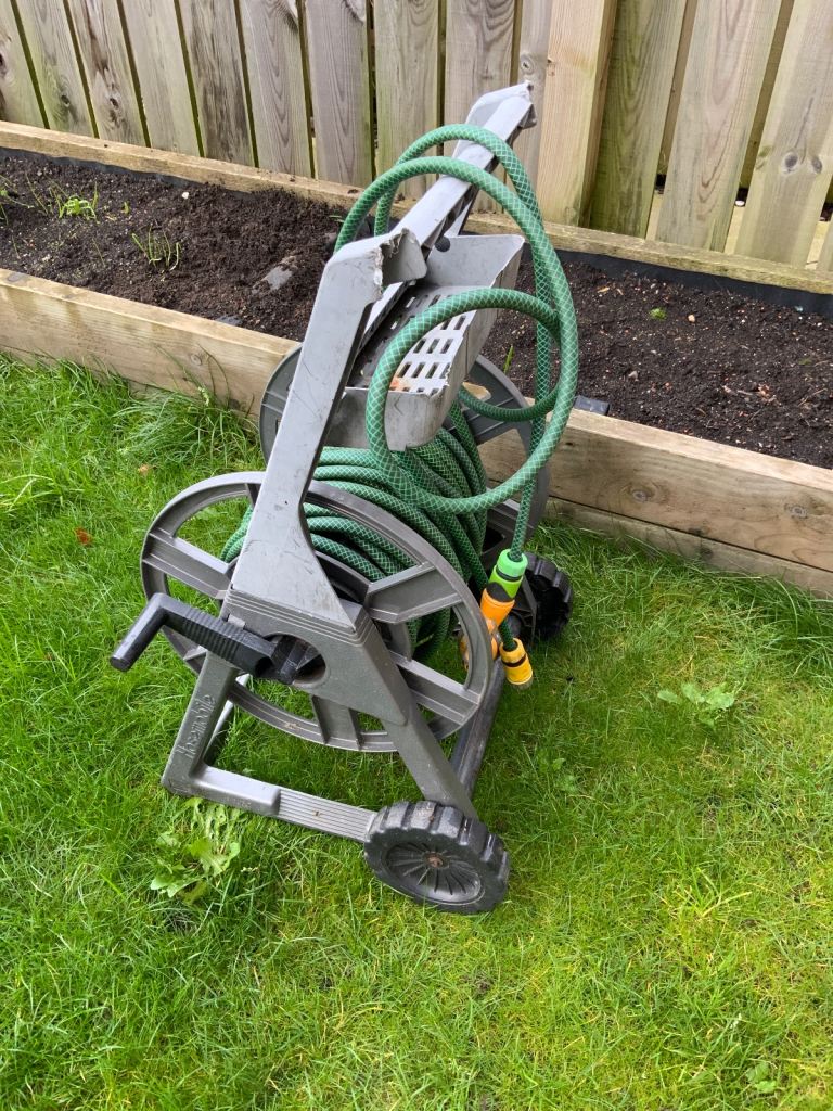 Garden hose on wheeled trolley with tap connector and adjustable spray end