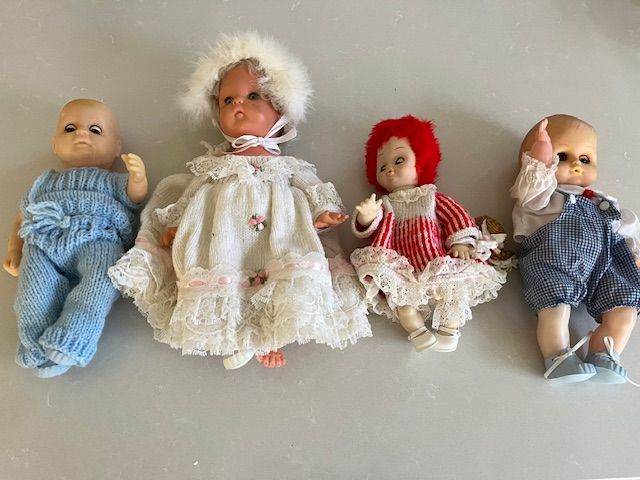 4 delightful plastic dolls with hand-made clothing.