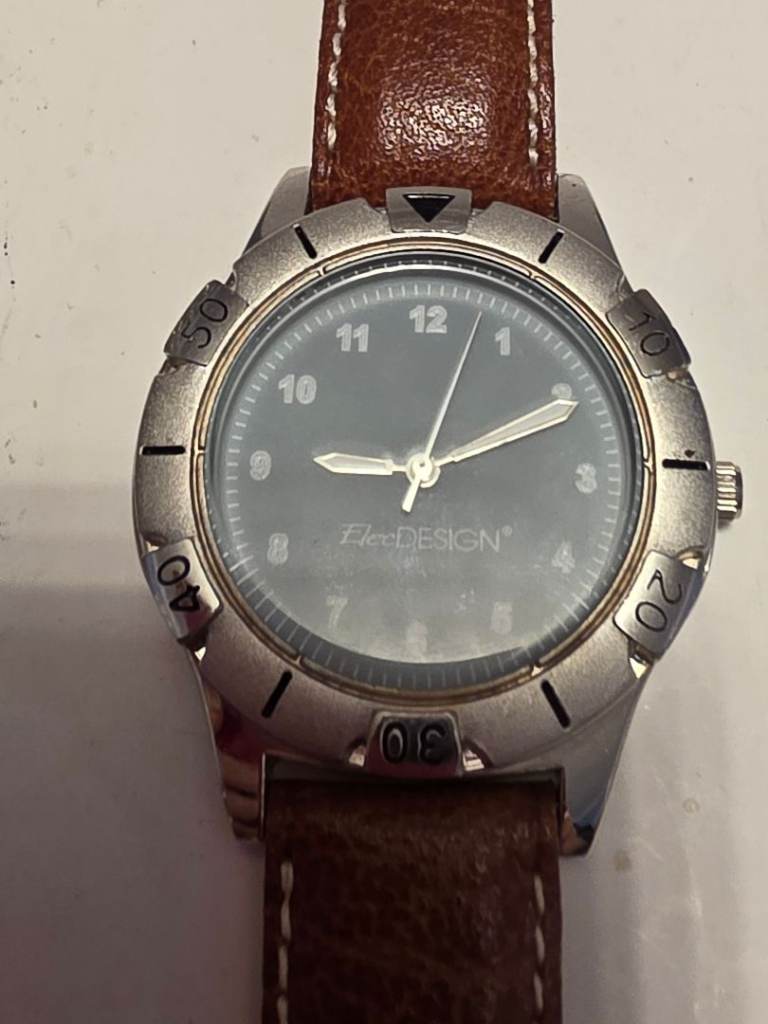 This is a vintage Sergio Valente Nite-Glo watch with a silver bezel, blue dial, 