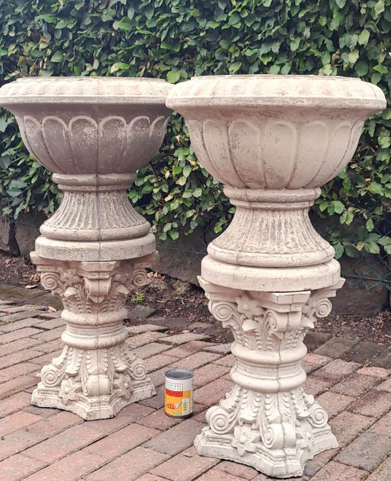 Match pair of stone garden urn planters on ornate stone plinths
