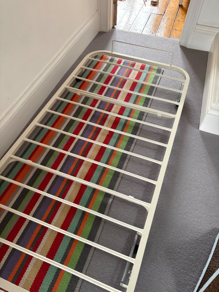 White metal day bed with trundle mattress beneath 