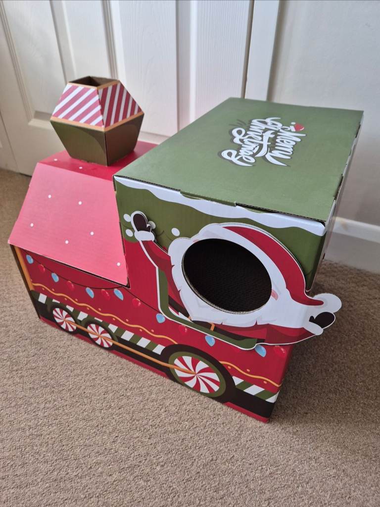 Festive train-shaped cardboard cat house and scratcher featuring holiday decorations