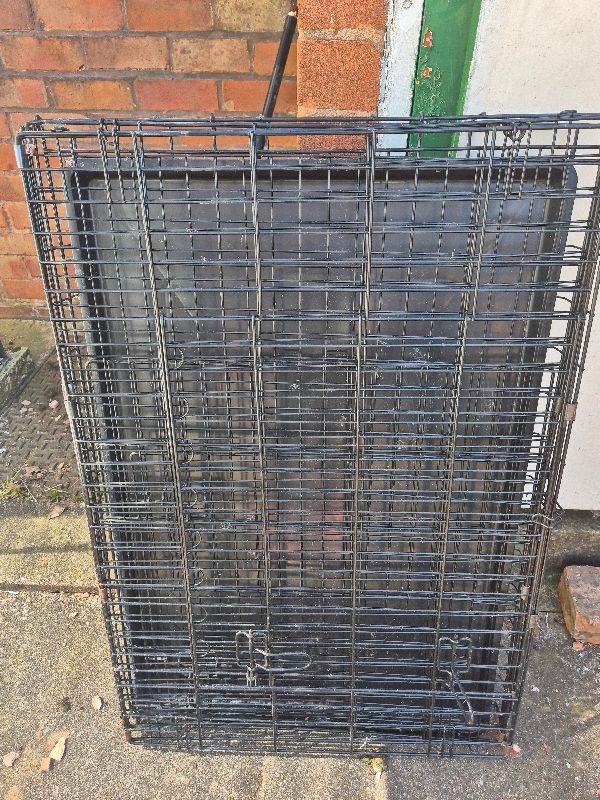 Large black metal dog crate with tray