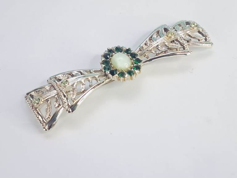 Vintage,silvertone  bow brooch in central light green stone surrounded by green rhinestones.