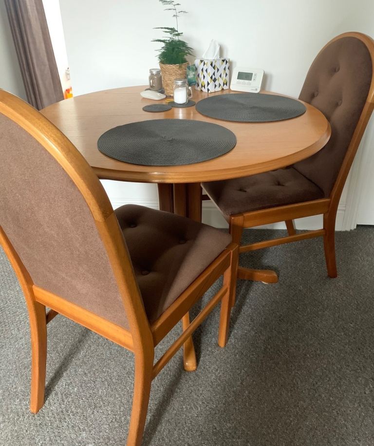 Round, extending solid wood dining table with 4 matching upholstered chairs.