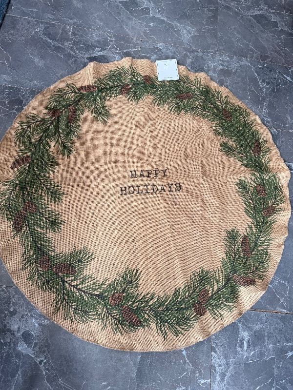 H&M Jute Christmas tree mat with a pine needle and pinecone print and "Happy Holidays" text