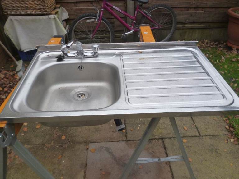 Stainless steel sit on type kitchen sink with taps and waste
