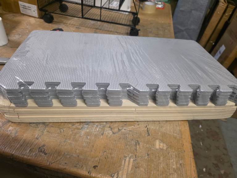 A new still packed pack of 20 light grey and cream foam mats.