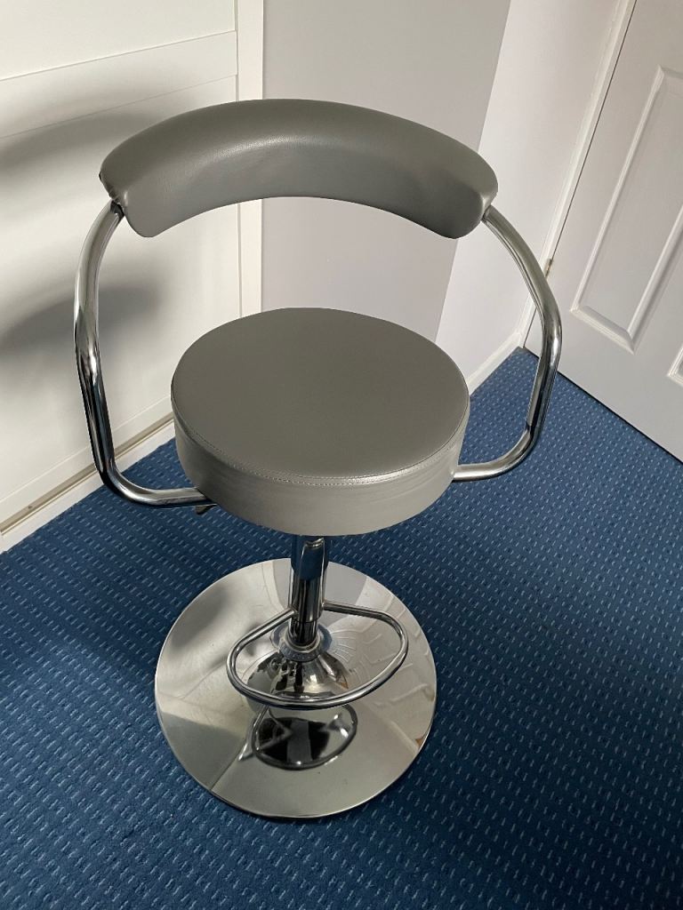 A grey bar stool with a chrome base and footrest