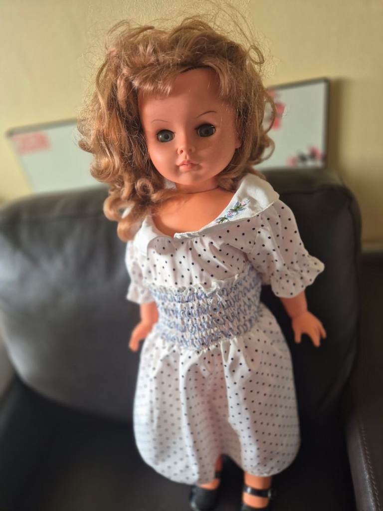 Classic doll wearing a white polka dot dress and black shoes