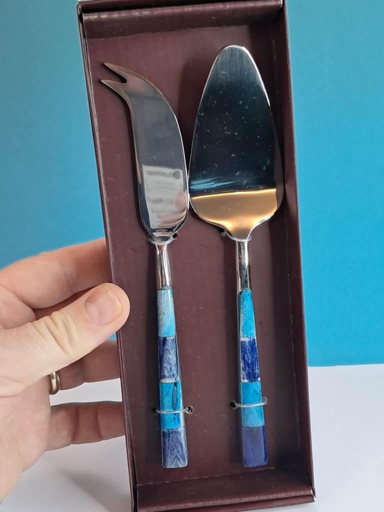 Traidcraft handmade stainless steel cheese serving tools with blue mosaic patterned handles.