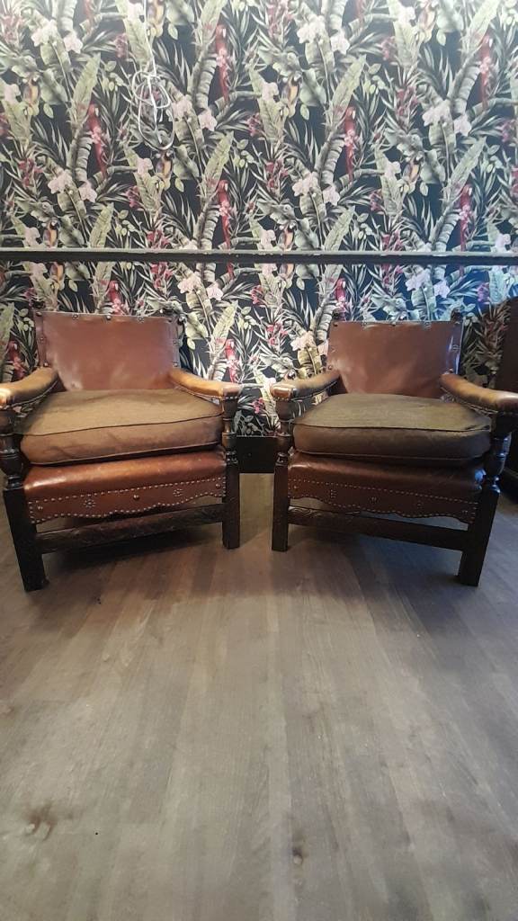 Pair of antique oak and studed leather lounge chairs with lion finials