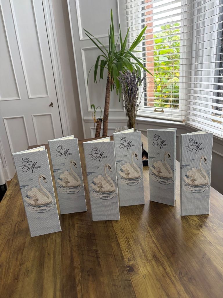 Linen hard cover menus with swan artwork 