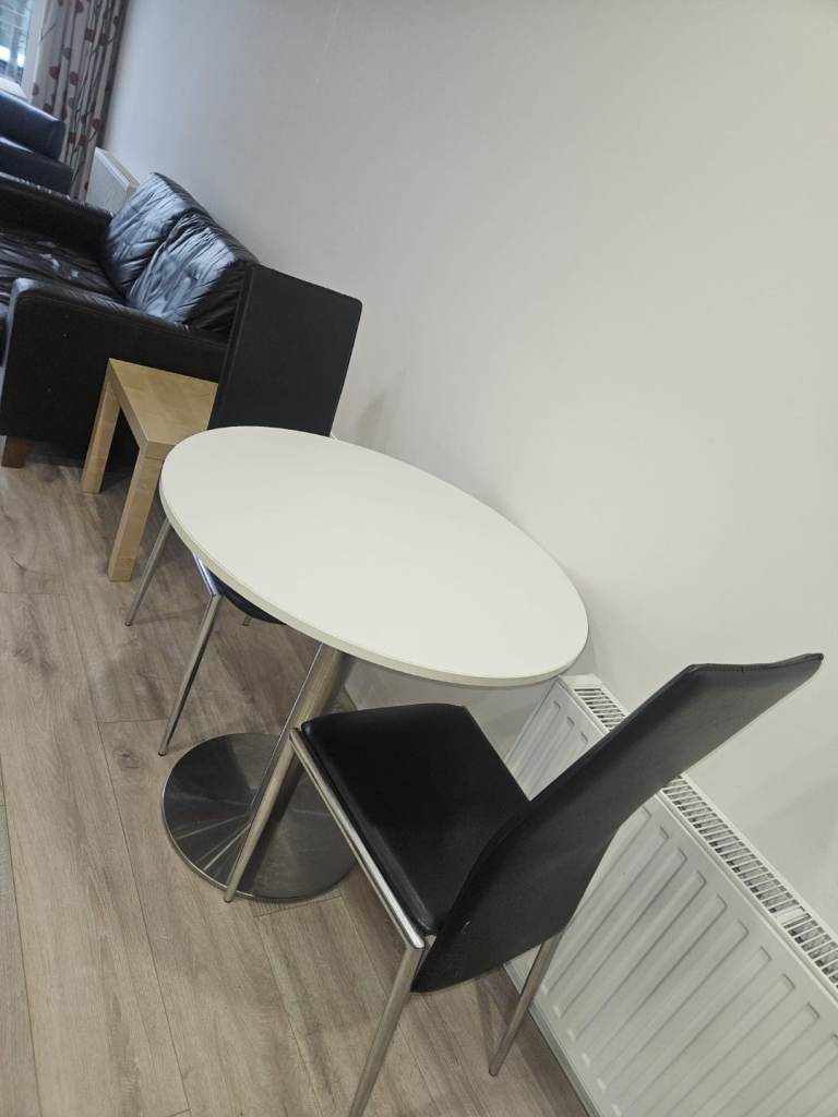 White wood round table and 2 black leather chairs 