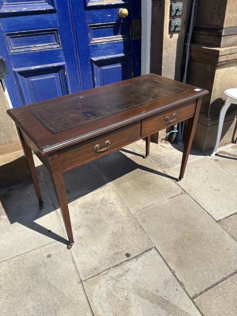 This lovely antique console desk features a classic leather top and two functional drawers