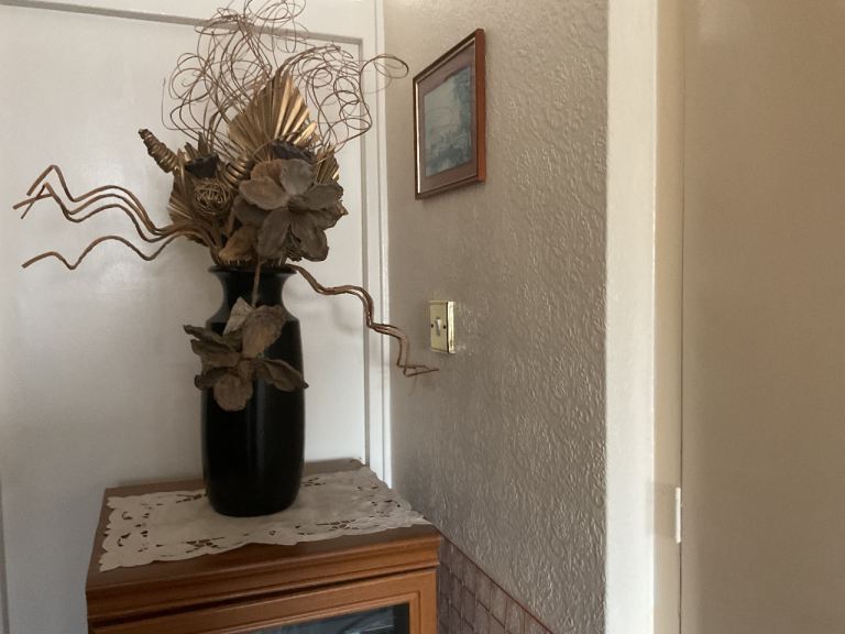 Black Vase with Gold coloured artificial flowers and different shaped artificial shapes.