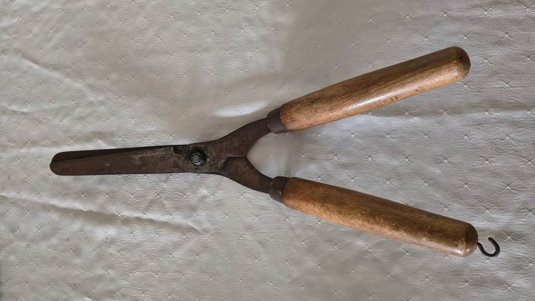 A pair of angled garden shears with wooden handles and one hook