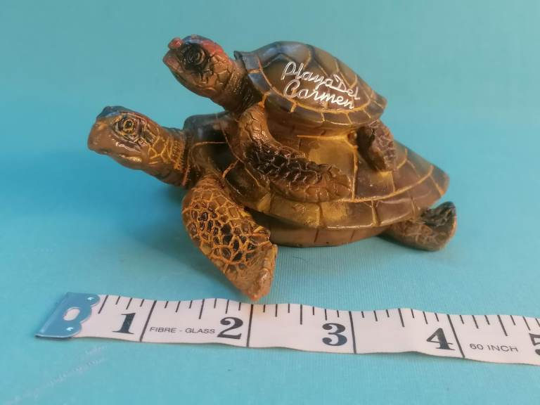 Ceramic glazed two sea turtles, with the  smaller turtle on top of the larger one.