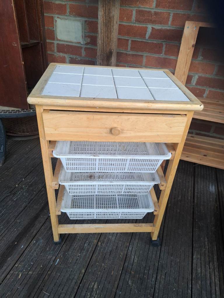 white tiled butchers block with drawer at the top and 3 baskets on wheels