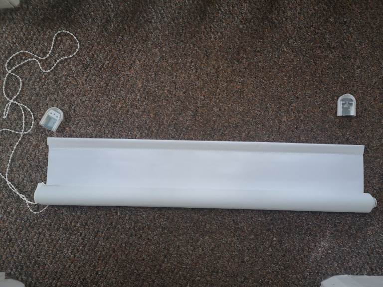 White roller blind with brackets.