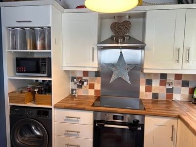 White kitchen with worktop oven, Hotpoint dishwasher, extractor fan, white composite sink and tap