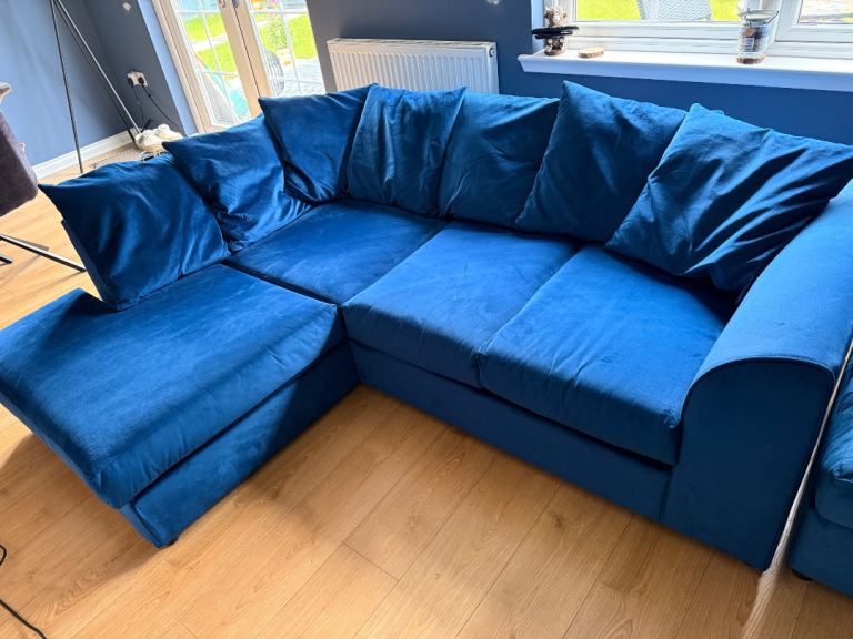 Blue velvet sofa with a matching footstool.