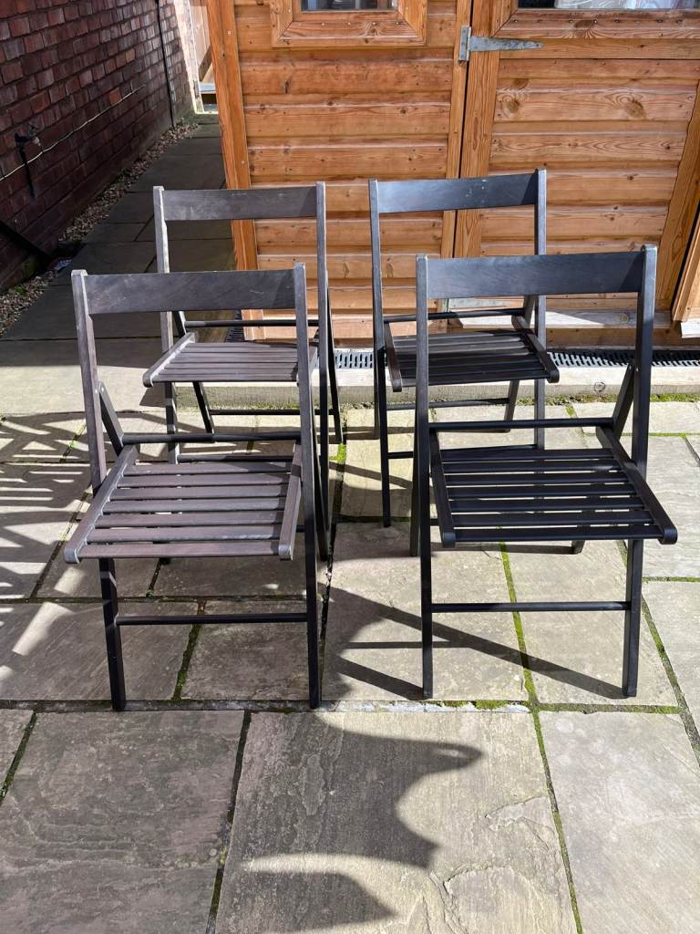 Four identical and hardly used wooden folding chairs.