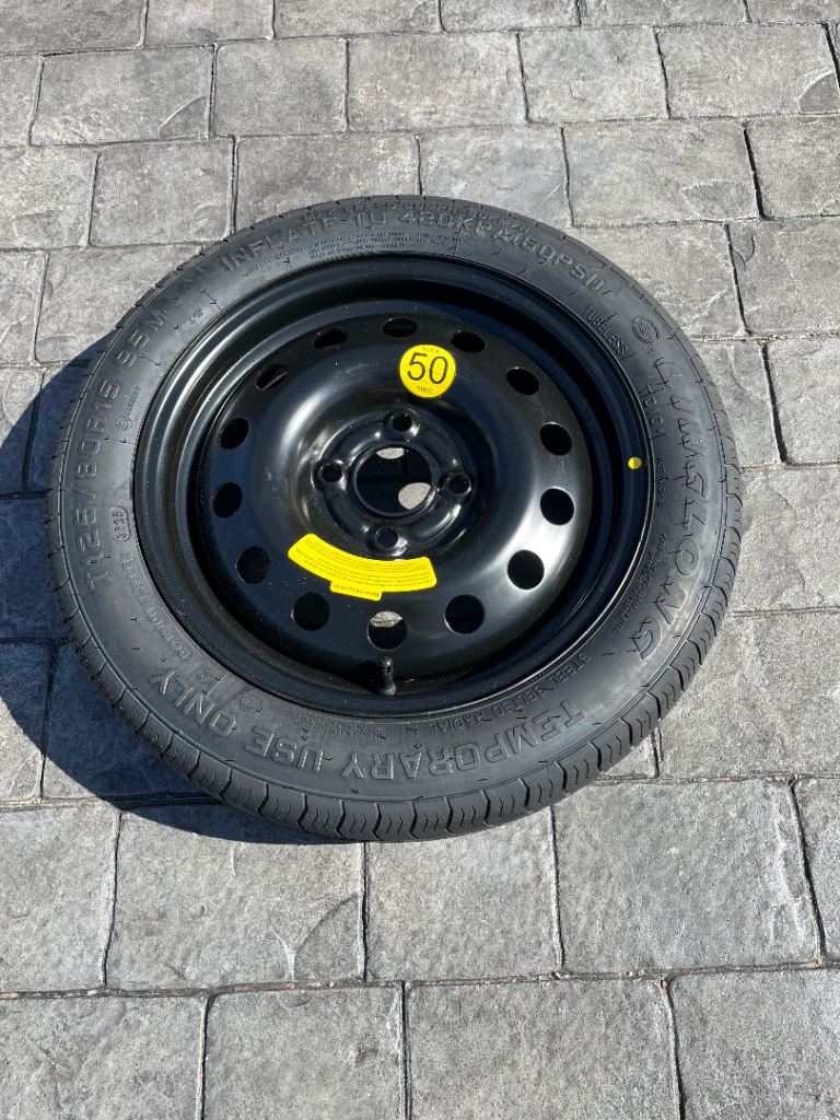Mini spare wheel T125/80R15 95M and fixing clamp.