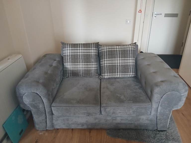 Grey Two-Seater Sofa with Plaid Cushions – Good Condition