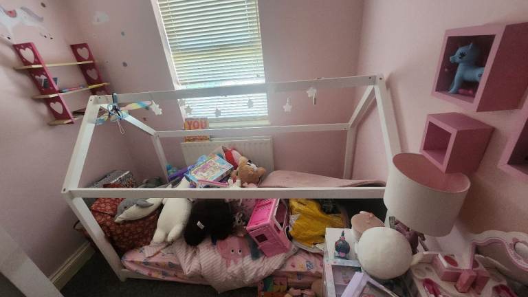 A child's single bed frame with slanted roof