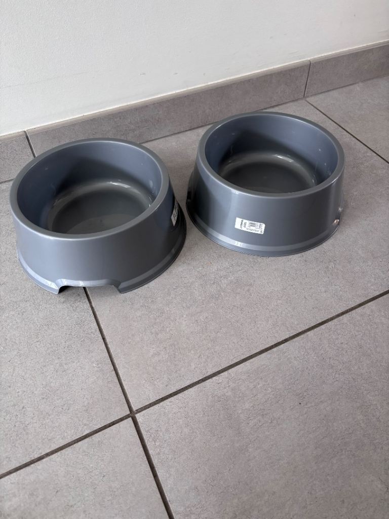 Two grey plastic pet food or water bowls