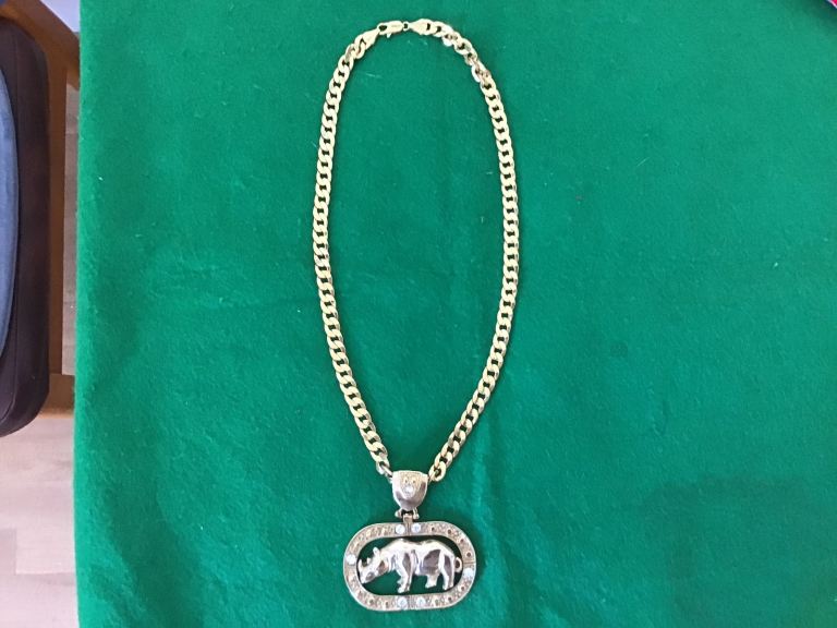 Gold tone necklace with Rhinoscerous pendant .