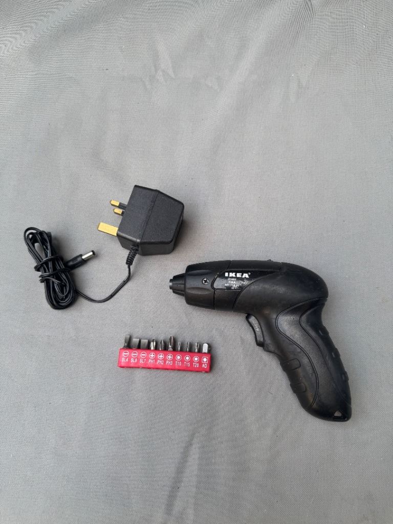 IKEA FIXA 3.6V cordless screwdriver with a black battery charger and a red bit set
