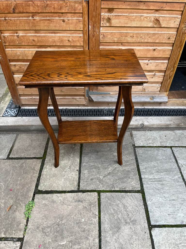 A vintage solid oak table with attractively shaped legs and under shelf.