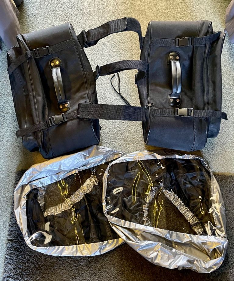 Large motorcycle soft throw over pannier bags with bright shiny elasticated rain covers.