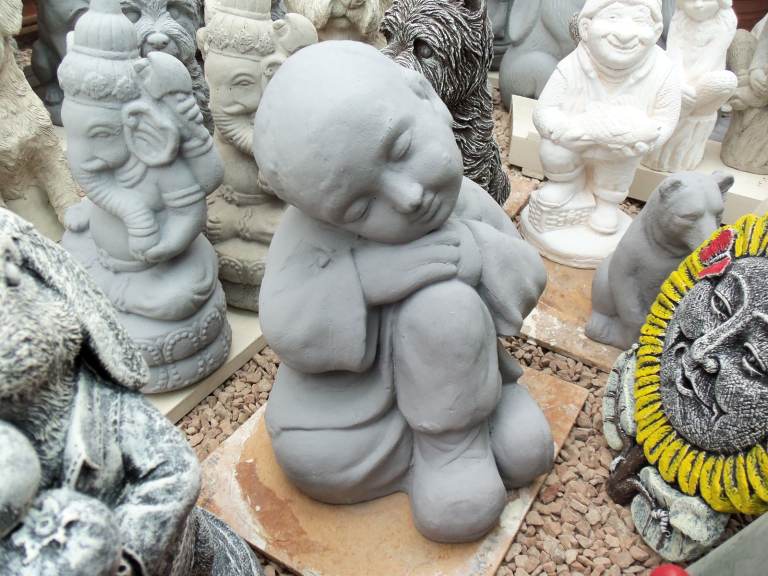 Concrete stone garden ornament statue of a resting Buddha boy