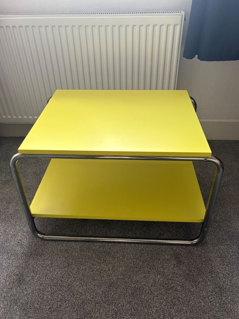 IKEA BAGGBODA side table featuring a light yellow tabletop and a chrome-plated steel frame
