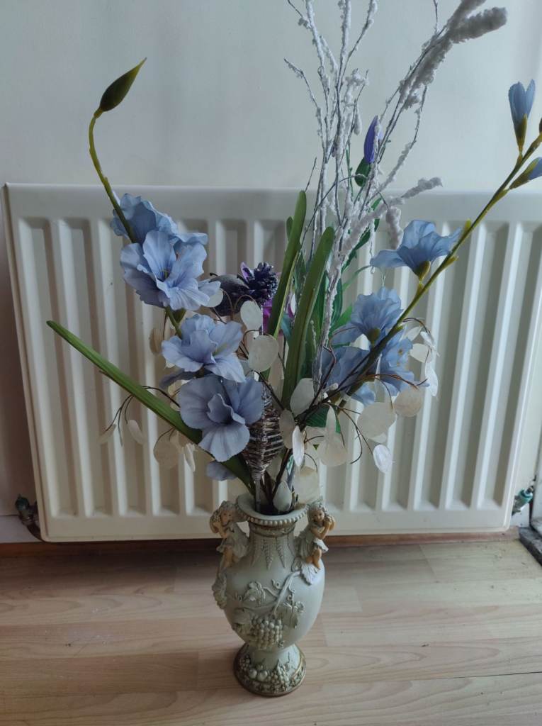 Small vase & flowers with an angel/cherub design. Vase 10-inches tall, tallest frond 36-inches.