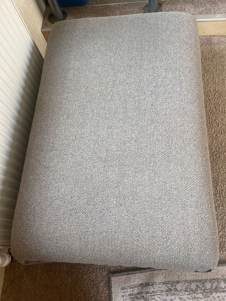 A grey fabric footstool