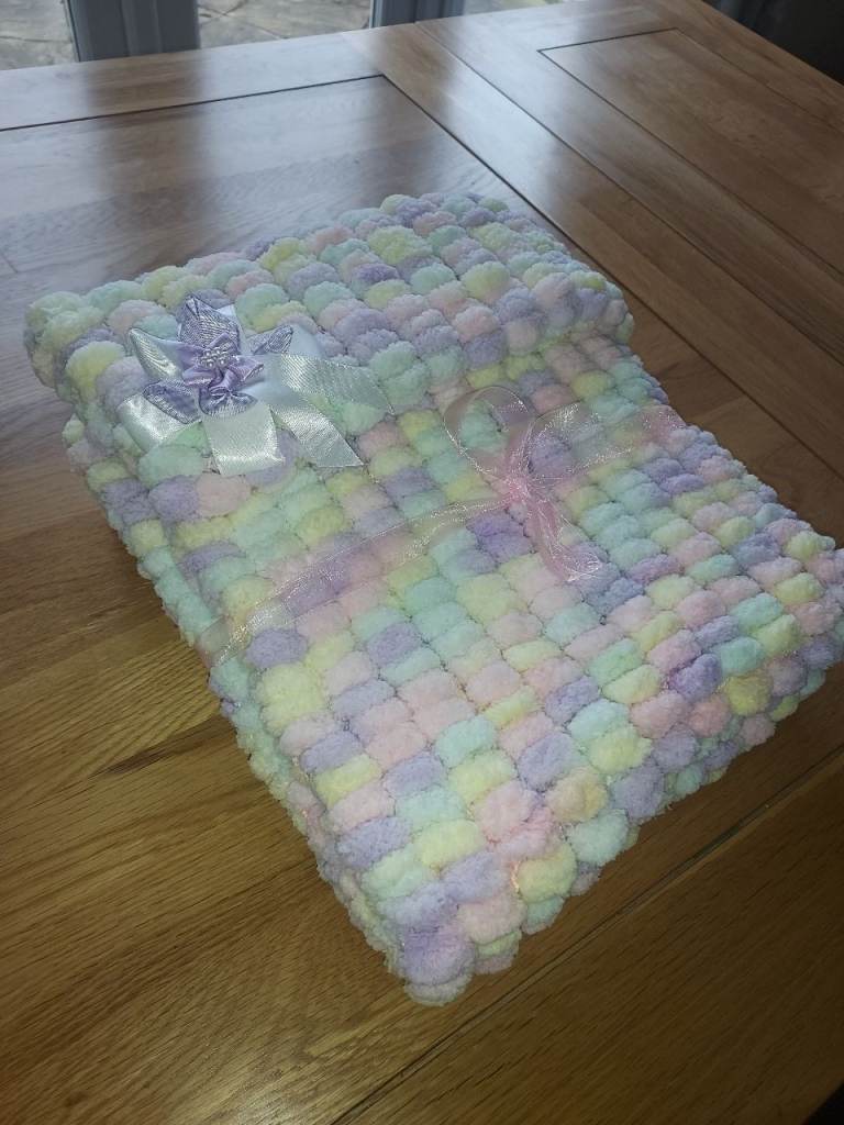 Brand new knitted baby pram blanket in pom pom wool. Various colours. Length 70cm x 53cm approx.