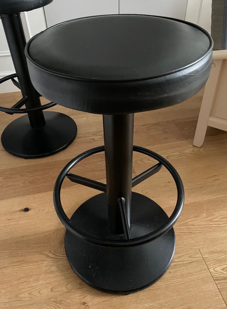 Bar stools in black leather padded seating and metal posts