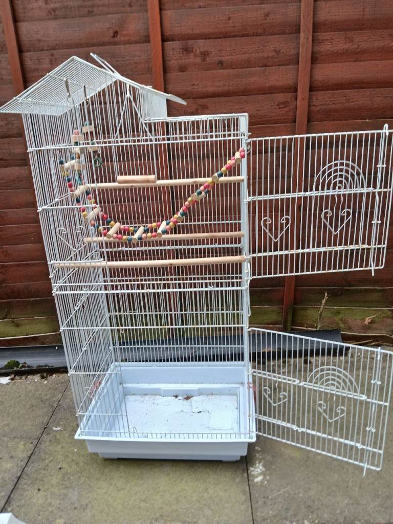 Large Bird cage with toys, perches, food containers and a litter tray.