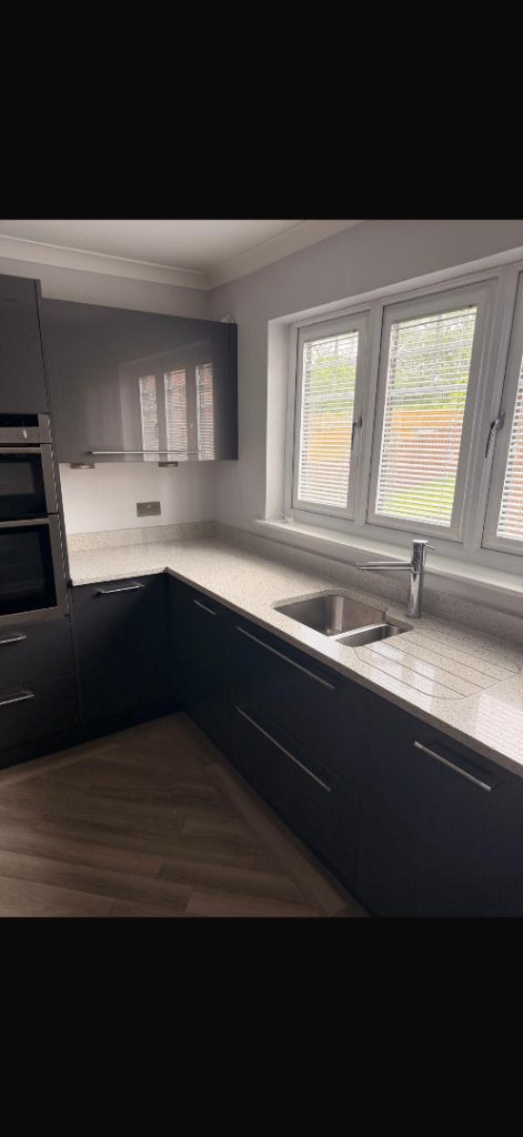 Grey gloss kitchen units with white speckled granite work tops 